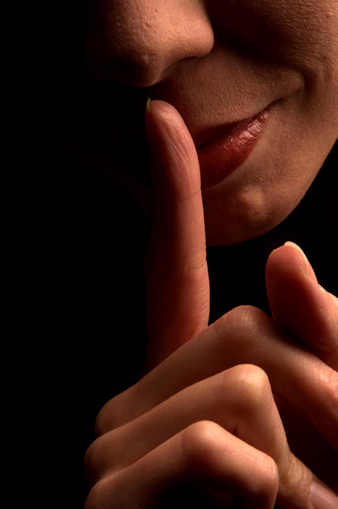 Un individu met un doigt devant sa bouche invitant au silence